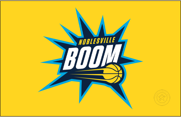 Noblesville Boom Logo Primary Dark Logo (2025/26-Pres) - The Noblesville Boom logo features a navy blue blast trimmed in cyan, with the team name displayed across it in white and yellow. The streaking yellow basketball from their NBA affiliate, the Indiana Pacers, is placed near the bottom of this blast or boom shape. SportsLogos.Net